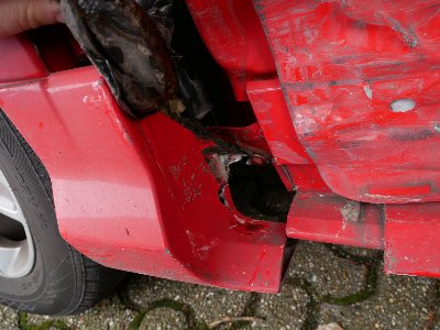 Seitenansicht eines roten Ford Kuga mit Unfallspuren und Lackabplatzungen an der linken Seite
