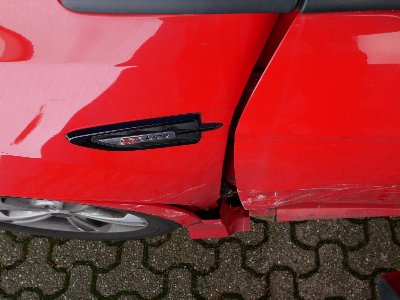 Linke Seite eines roten Ford Kuga mit auffälligen Schrammen und Beulen nach einem Seitenzusammenstoß