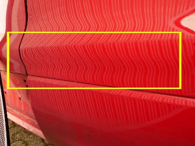 Roter Ford Kuga mit tiefer Delle und abblätterndem Lack an der Fahrerseite, verursacht durch einen Verkehrsunfall