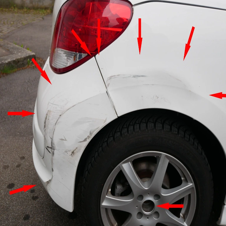 Nahaufnahme der Unfallspuren am hinteren rechten Radkasten eines weißen Peugeot 307 Cabrio.