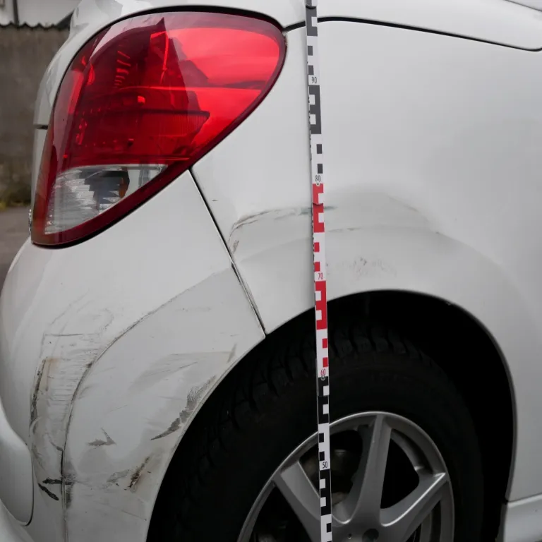 Detailaufnahme von Karosserieschäden an einem weißen Auto für ein Schadengutachten