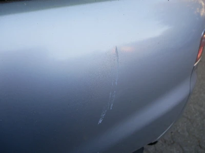 Detailaufnahme von Lackschäden an der linken Tür eines silbernen Seat Ibiza, entstanden durch Türkontakt