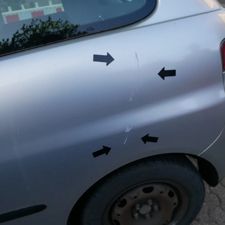 Nahaufnahme der Schäden an der linken Fahrzeugseite eines silbernen Seat Ibiza durch Türanschlag