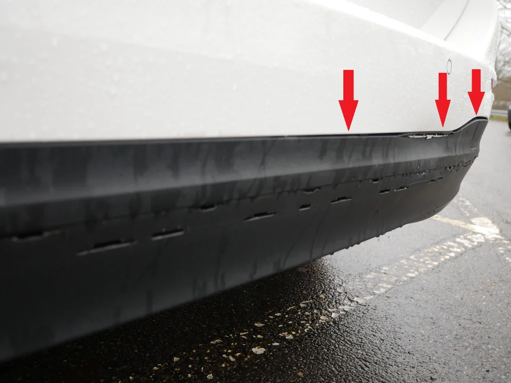 Seitenansicht eines weißen Tesla Model S, zeigt Kratzer und Dellen an der linken vorderen Ecke